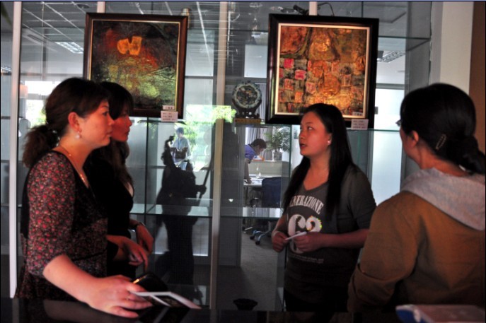 图为学生为竞拍者讲解漆画内涵