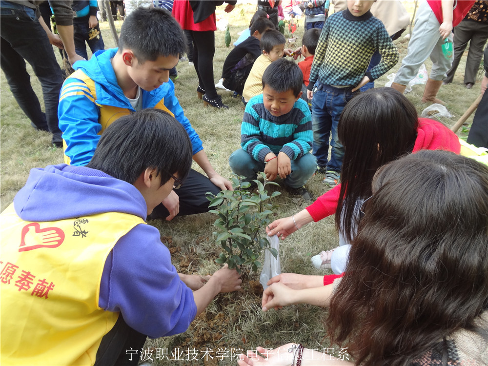 图为：志愿者们和小朋友们一起种树
