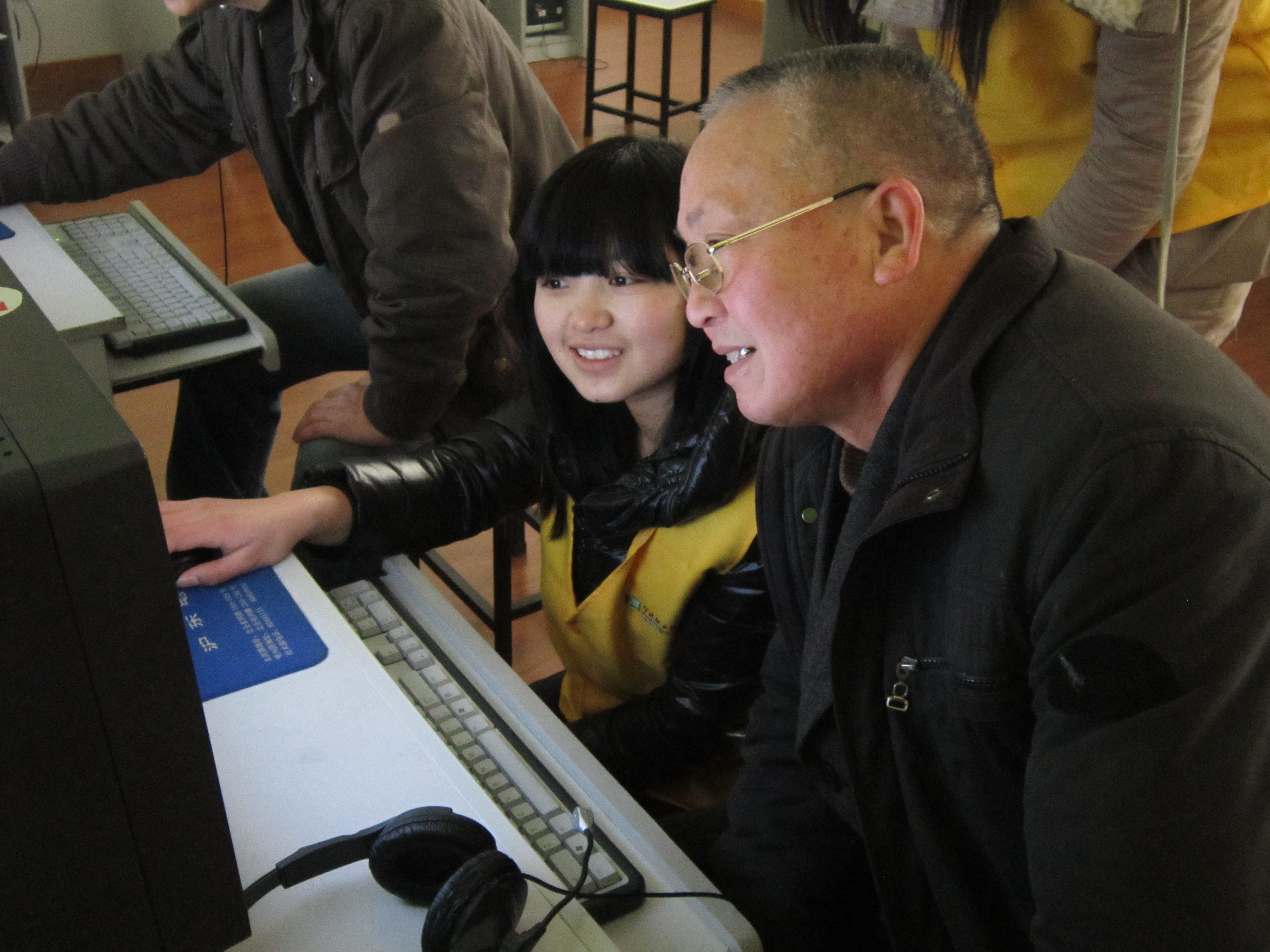 图为：志愿者在指导居民使用电脑