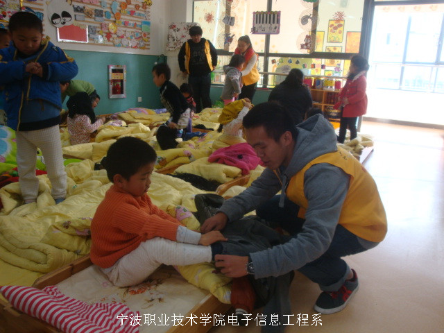 图为：志愿者在为小朋友整理内务