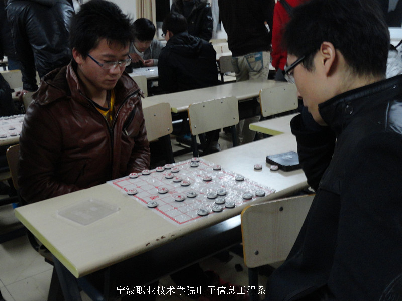 图为：棋艺大赛现场同学和老师在切磋棋艺 