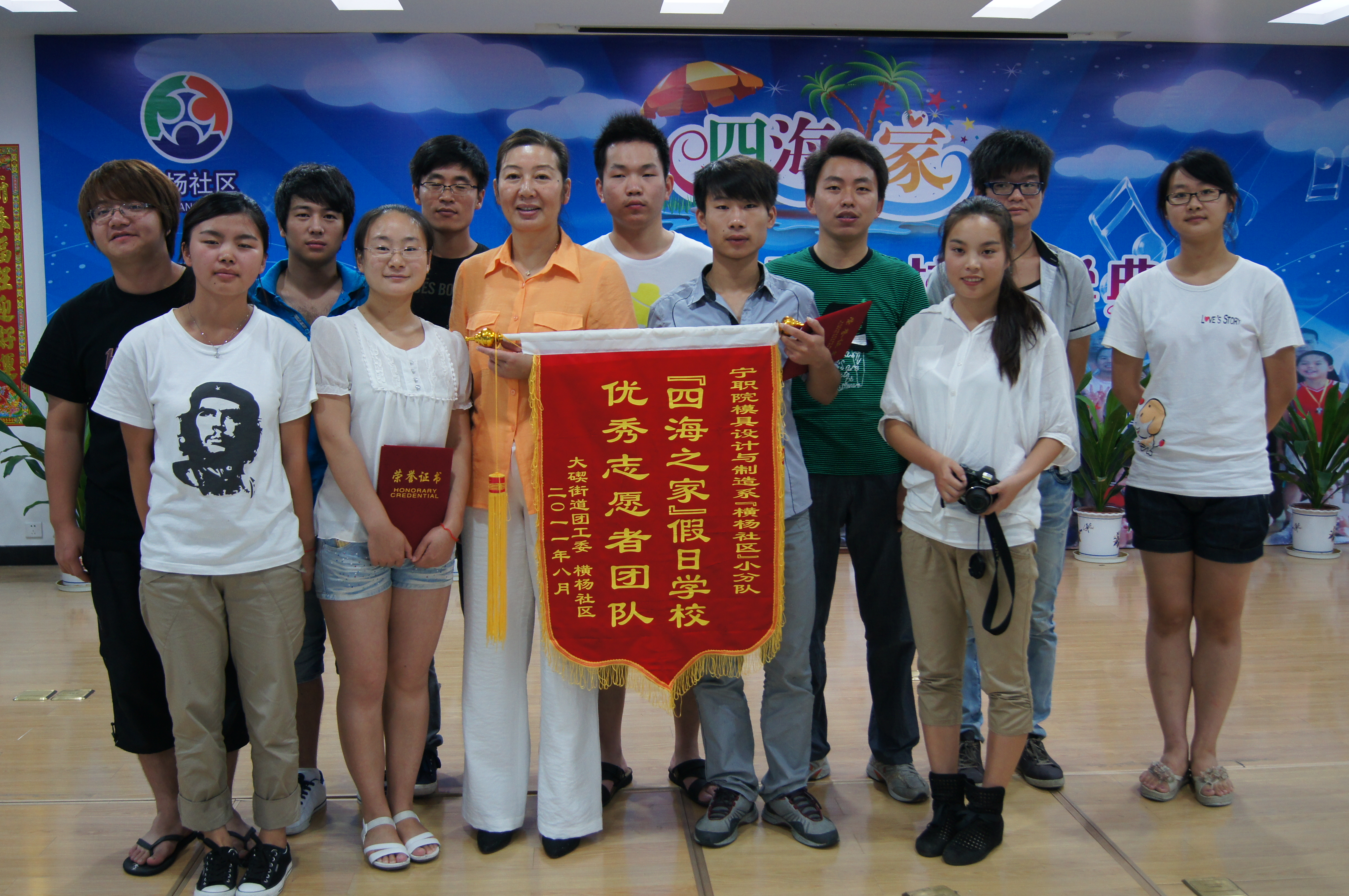 图为：社区郁亚萍主任为支教志愿者团体颁发优秀志愿者团队锦旗