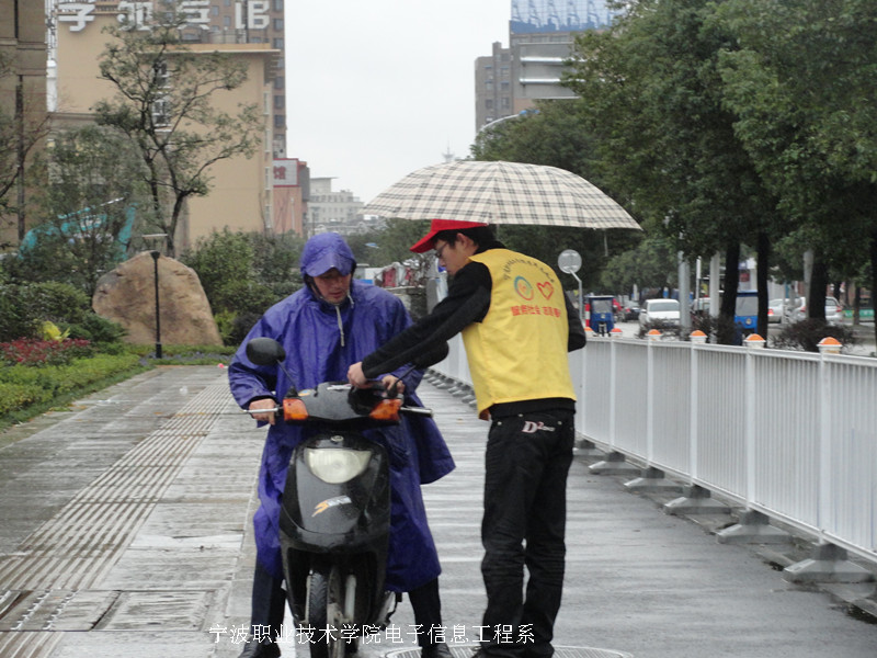 图为：志愿者为路人发放宣传单和讲解