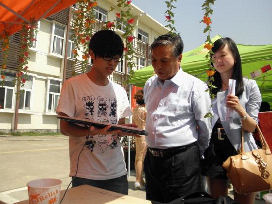 图为：我系同学正在向中科院院士、我院院长何贤土老师介绍活动项目