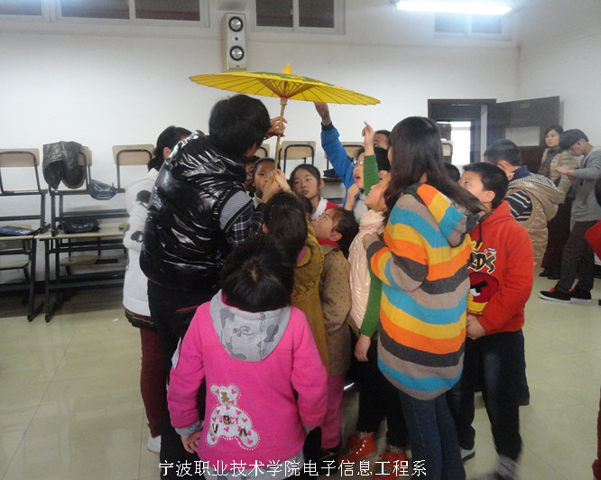 图为：伞艺工作室的同学们为小朋友介绍伞艺的制作过程